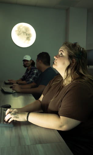 A person working in a control center with the moon in the background.