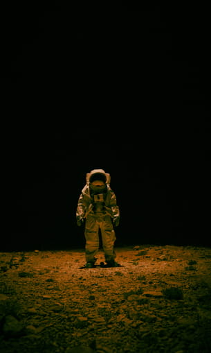 An astronaut in a spacesuit standing on the surface of a planet.