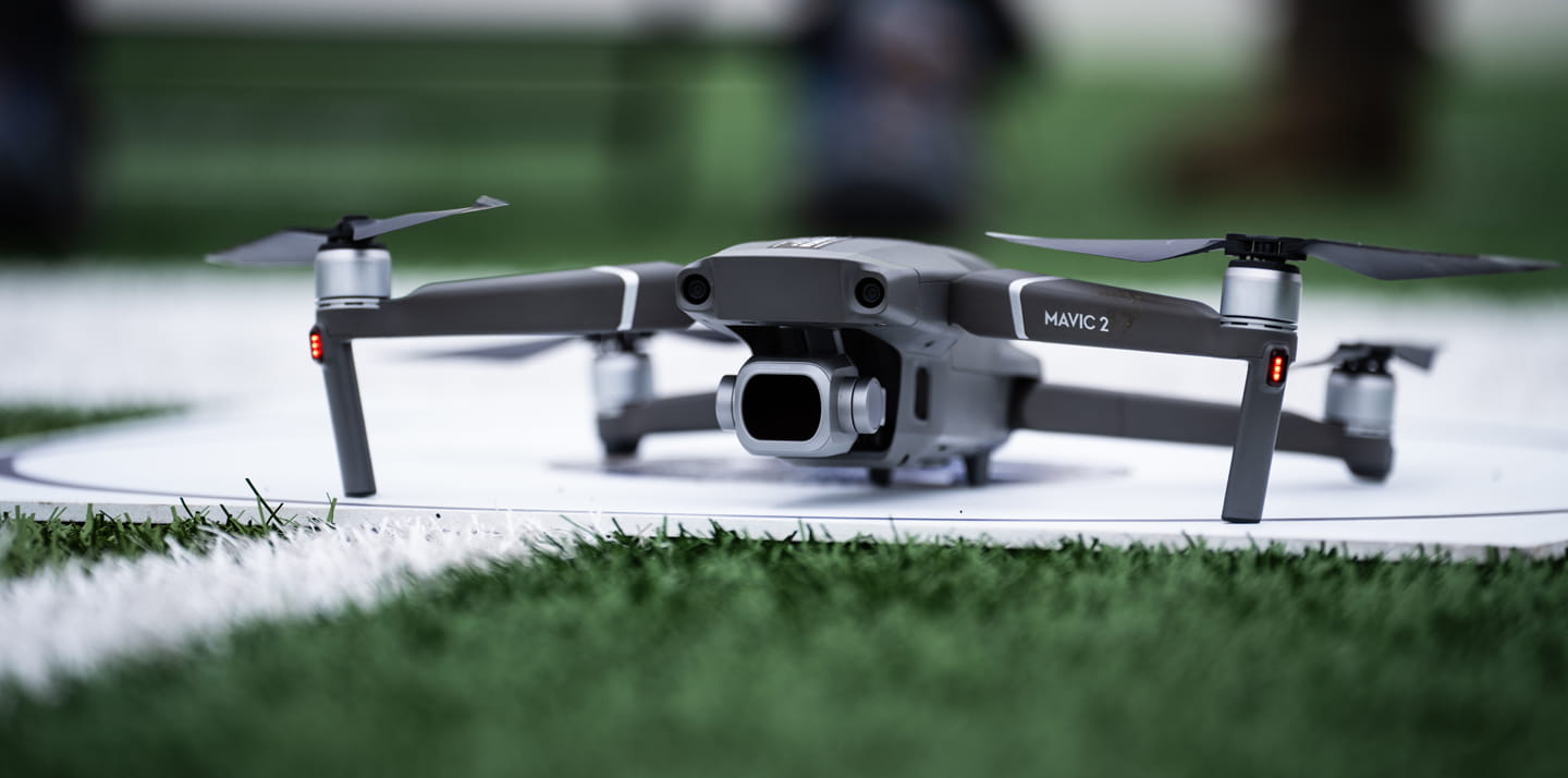 A drone resting on a white platform in a green field.