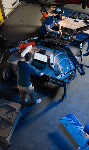 From above, two people work together on a large drone.