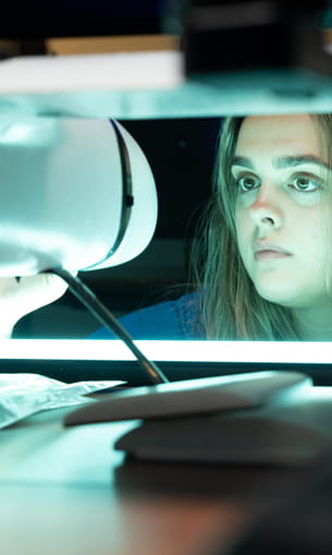 A person examining a drone at eye level in a laboratory.
