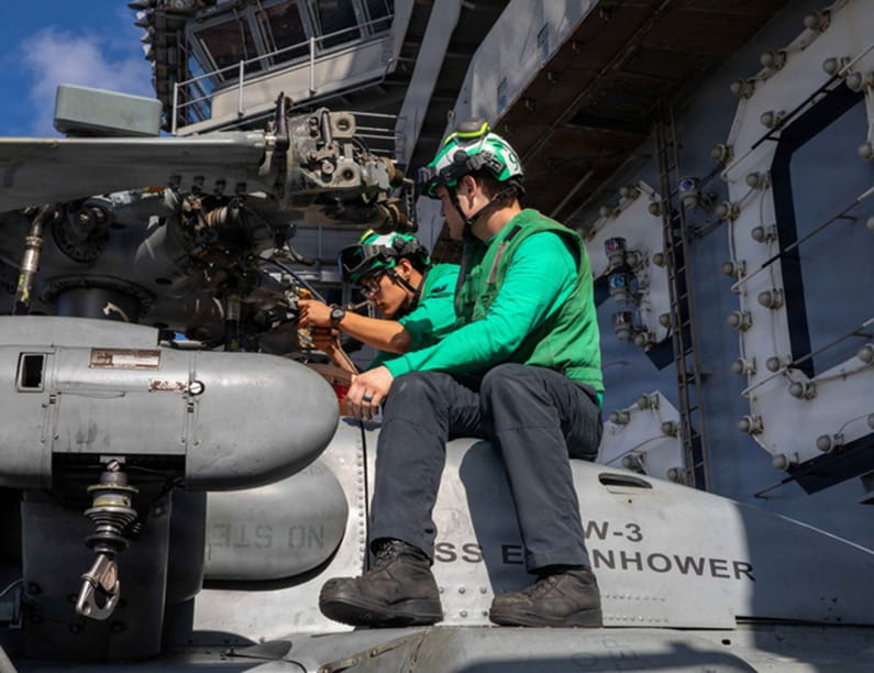 Two technicians work on a helicopter