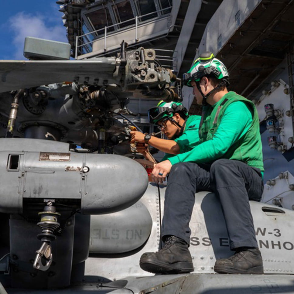 Two technicians work on a helicopter