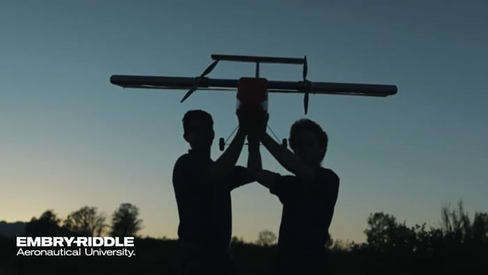 Two people holding a drone