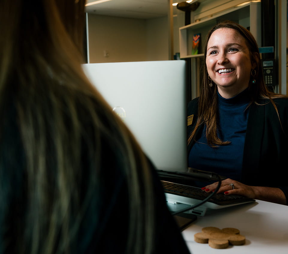 Student services staff smiles across a desk at a student.