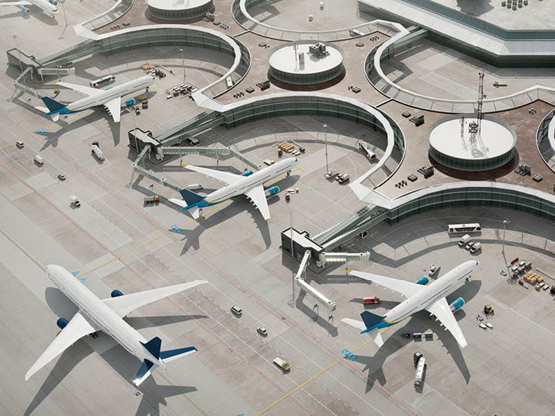 Aerial view of an airport with multiple commercial airplanes parked in curved bays.