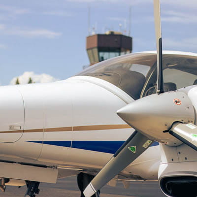 A close-up of a small aircraft’s front window and propeller.