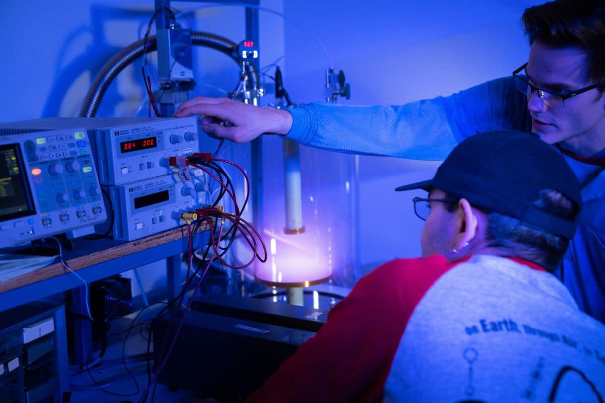 Dr. Jeremy Riousset and senior Jonas Rowan (standing) fine tune the glow discharge plasma chamber. (Photo: Embry‑Riddle / Bill Fredette-Huffman)