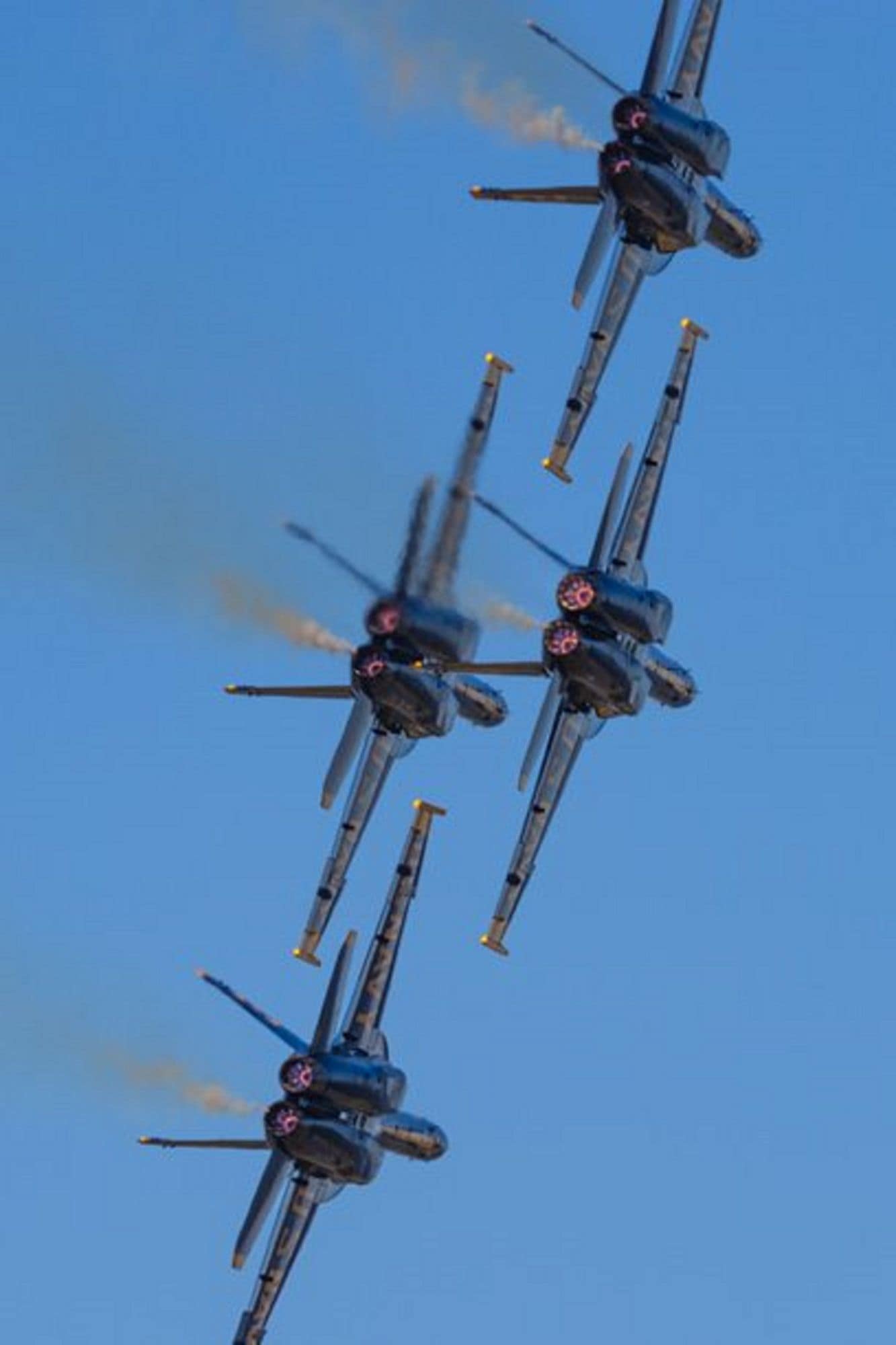 Four Blue Angel F-18 Hornets with full afterburners flying away from air show center in tight formation. (Photo: Bastien Melin via @ocular.photo on Instagram)