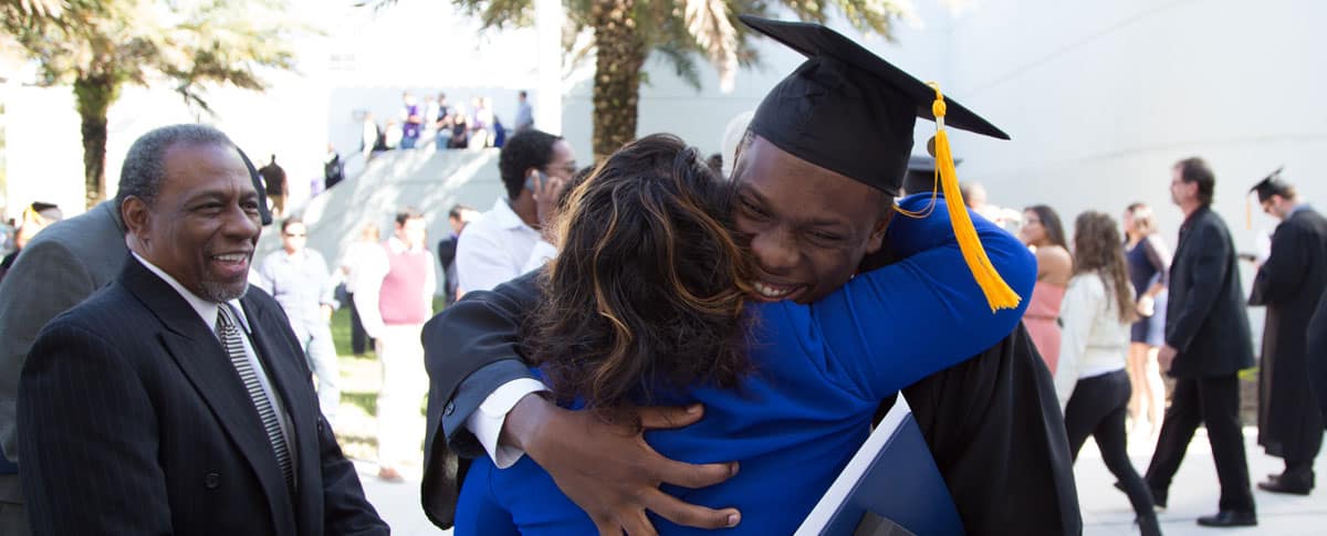 A student hugs his mom at graduation.