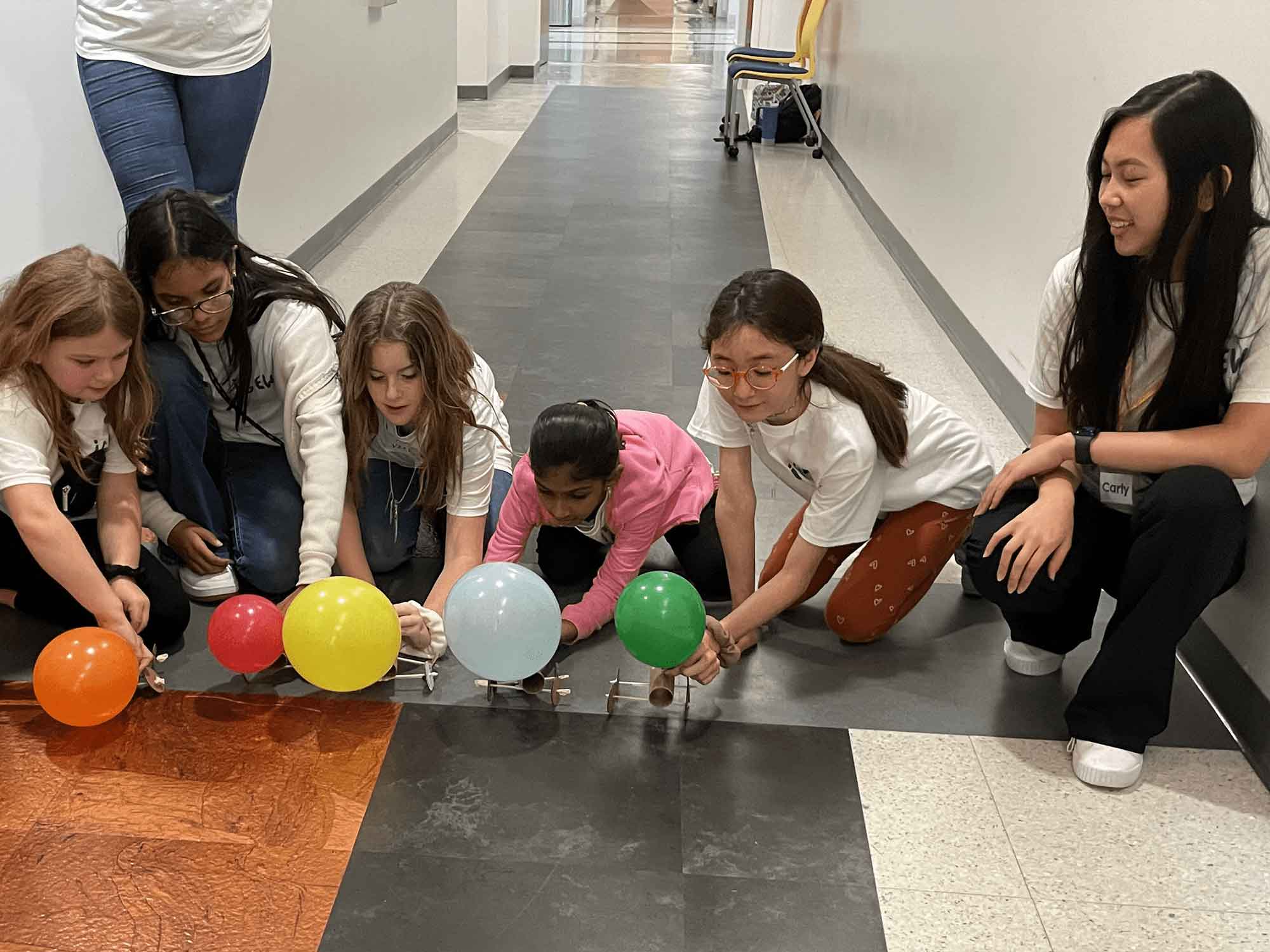 SWE volunteer Carly McDonald (right) helps young engineers get ready to test out the balloon cars they just built. (Photo: Embry‑Riddle)