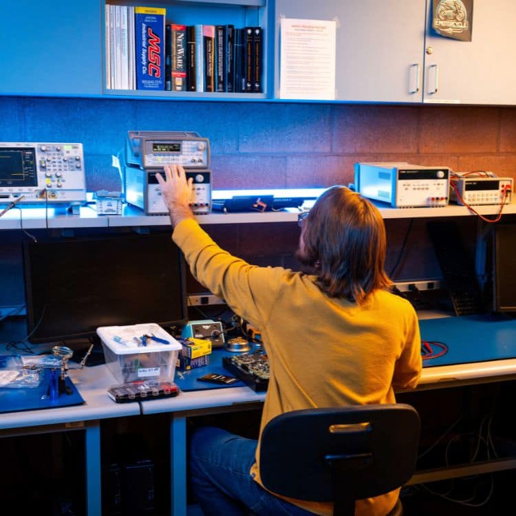 Embry‑Riddle student Michael Stalford sits in the senior design lab, configuring an oscilloscope.