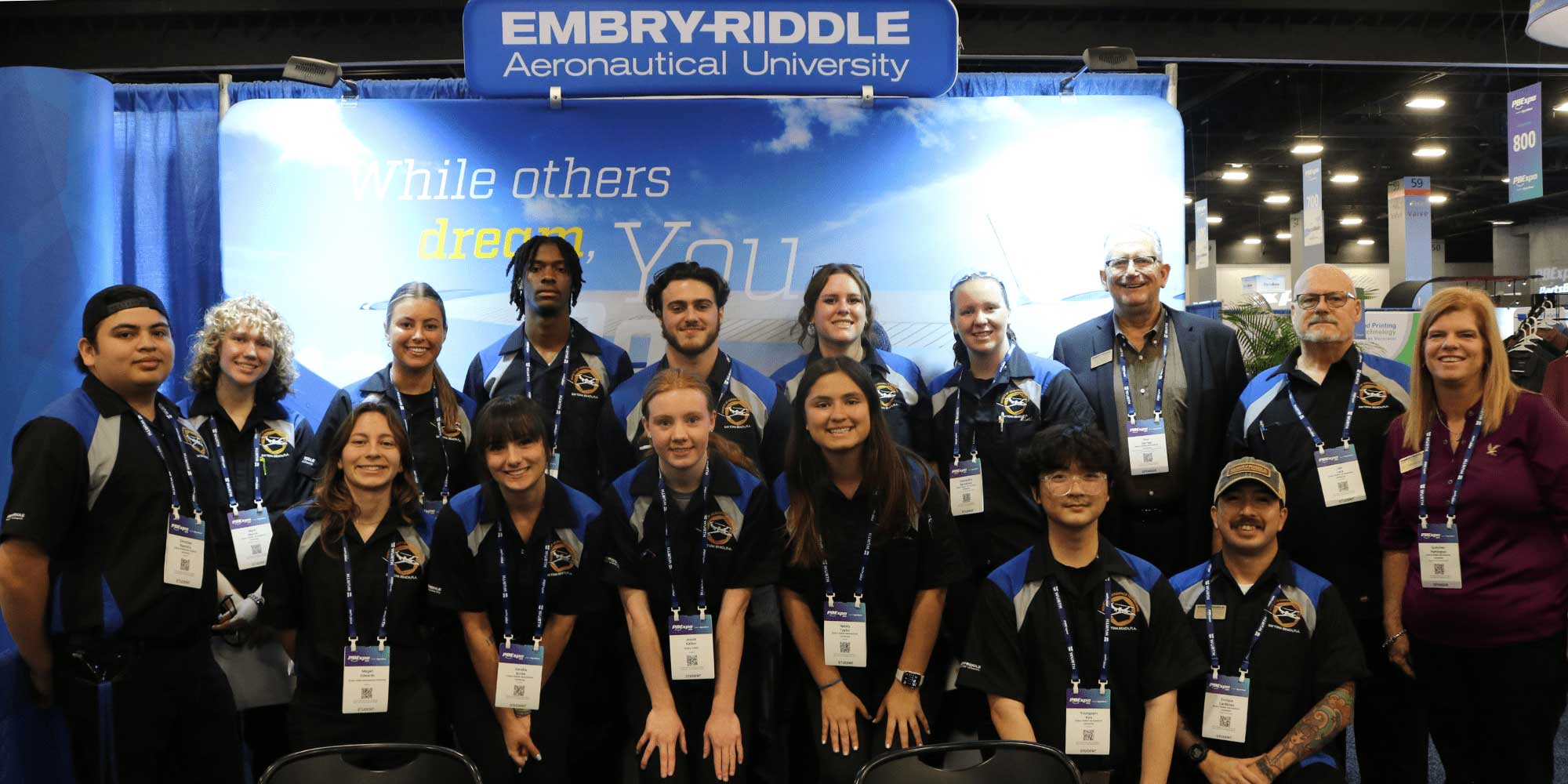 AMS student team poses in front of blue backdrop.