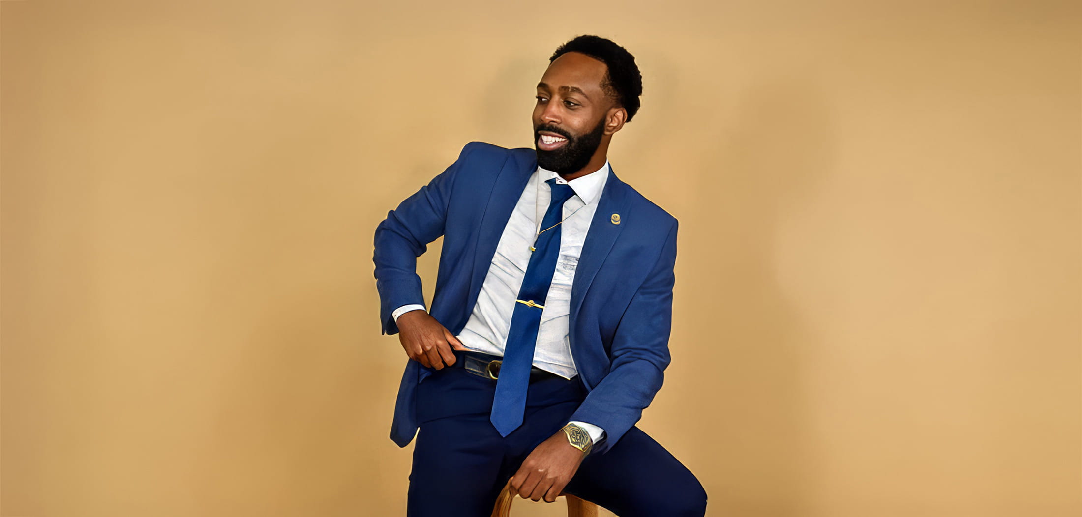 Dellavonte Hune in a blue suit sitting on a stool. 