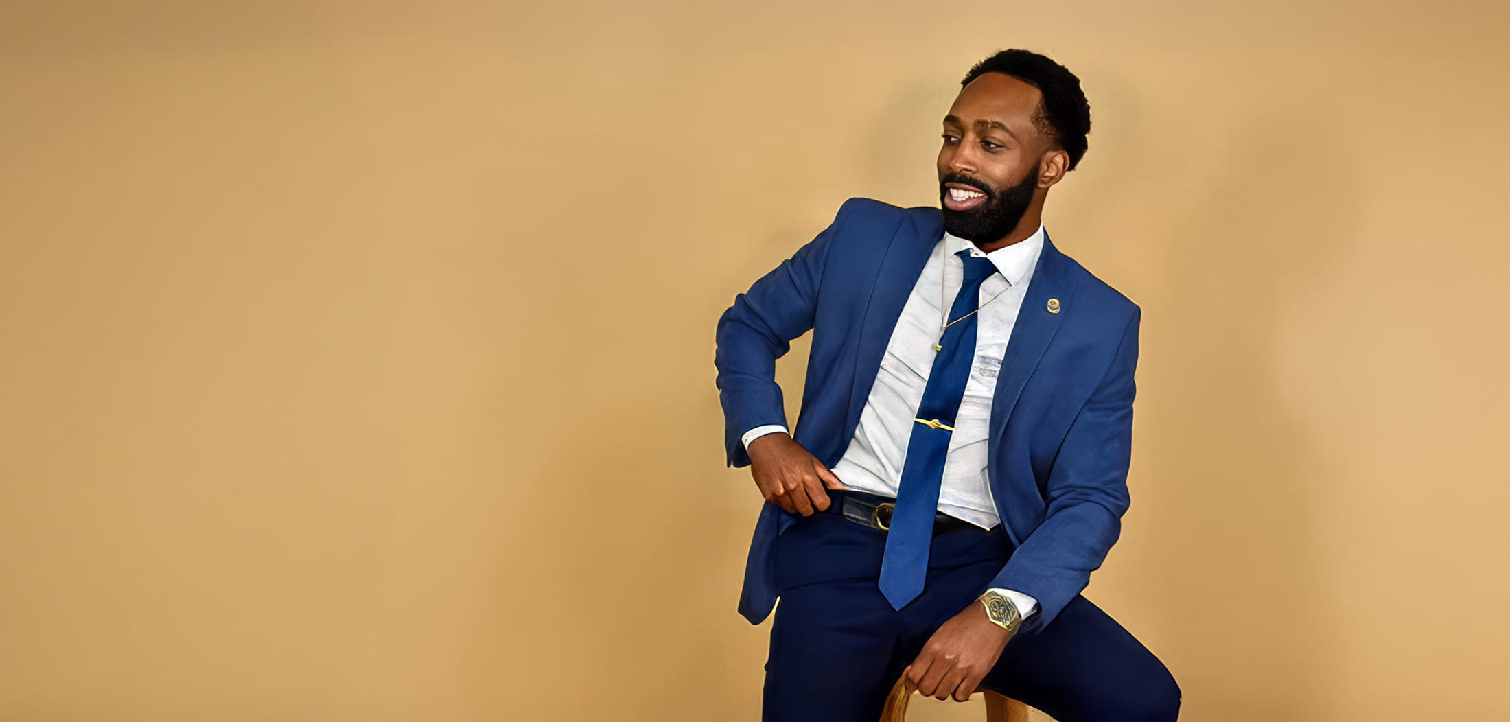 Dellavonte Hune in a blue suit sitting on a stool. 