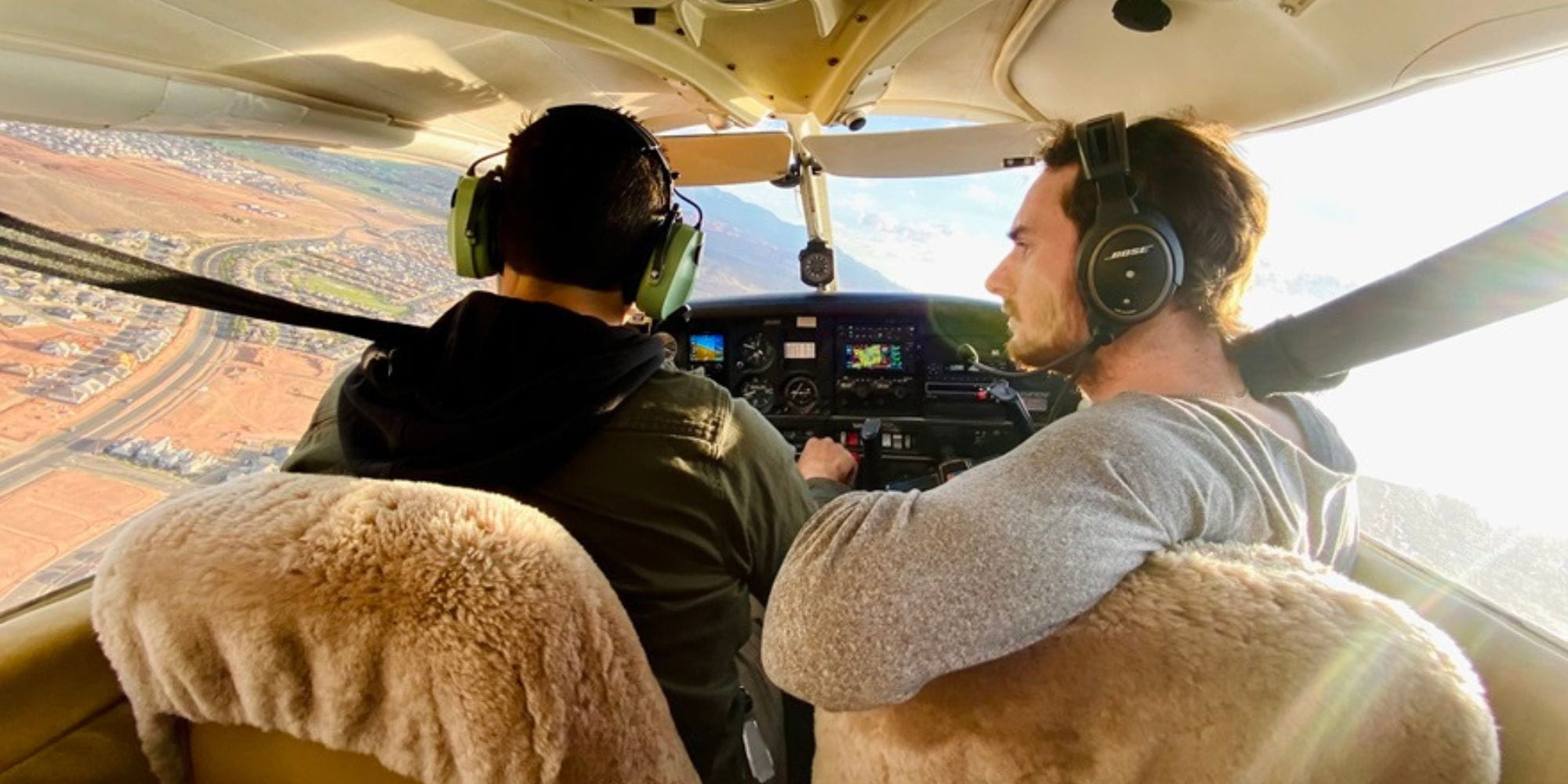Two people seated in the cockpit of a small aircraft during flight.