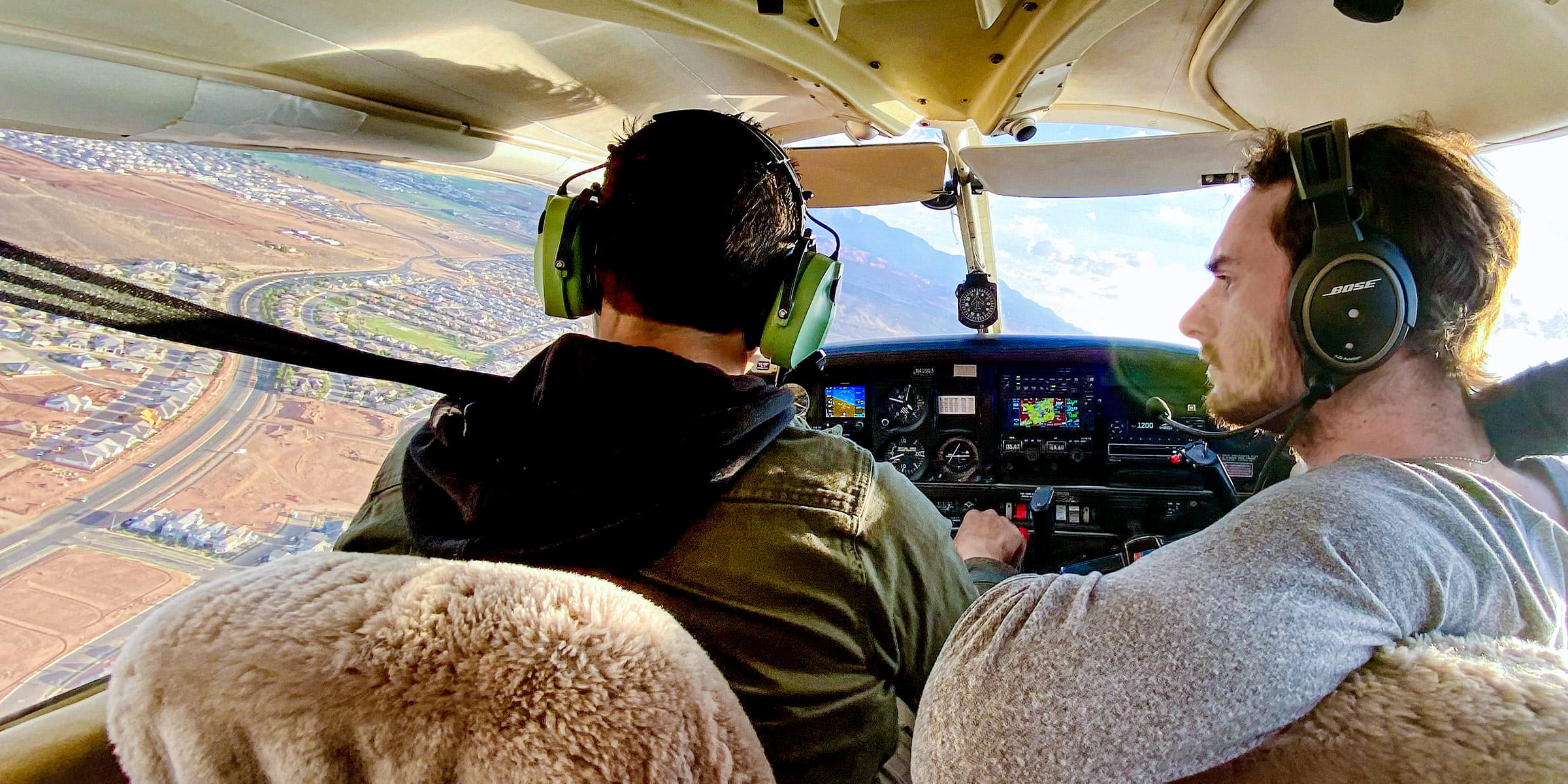 Two people seated in the cockpit of a small aircraft during flight.