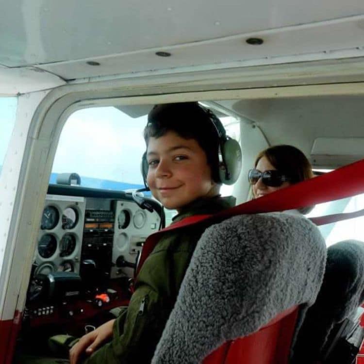 Young boy sits in cockpit of airplane.