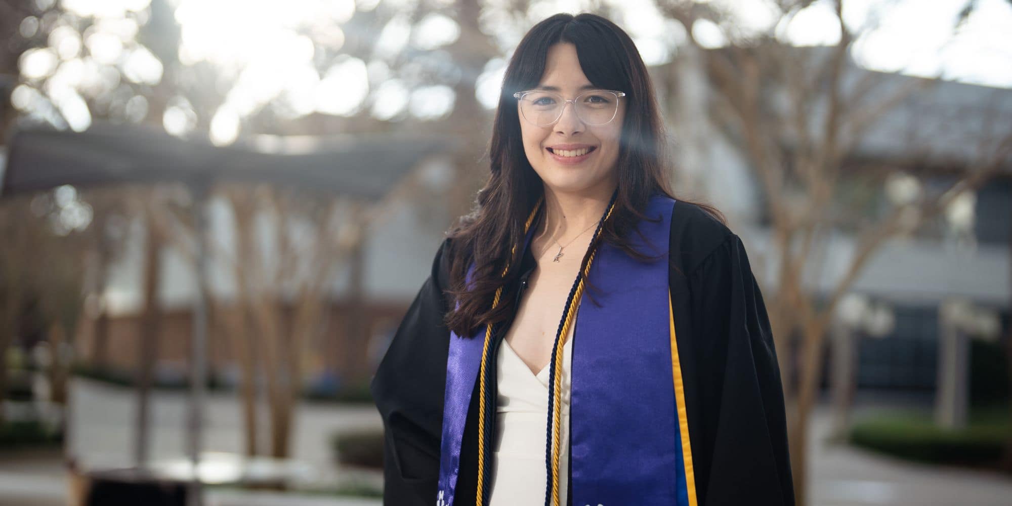 Woman stands in cap and gown.