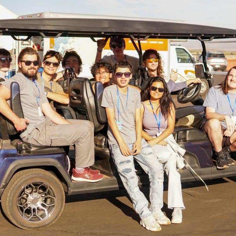 Ten people sitting on golf cart at airport.