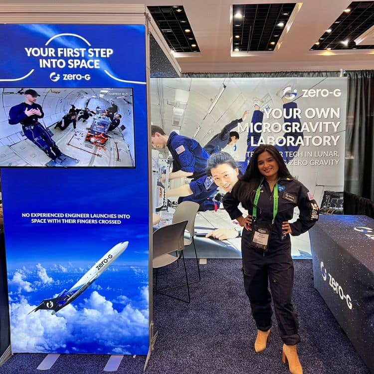 Girl stands next to banner advertising Zero G flights.