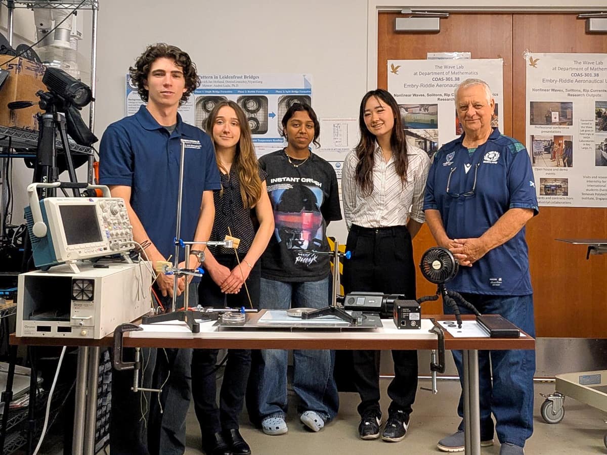 Five people in a line next to lab equipment