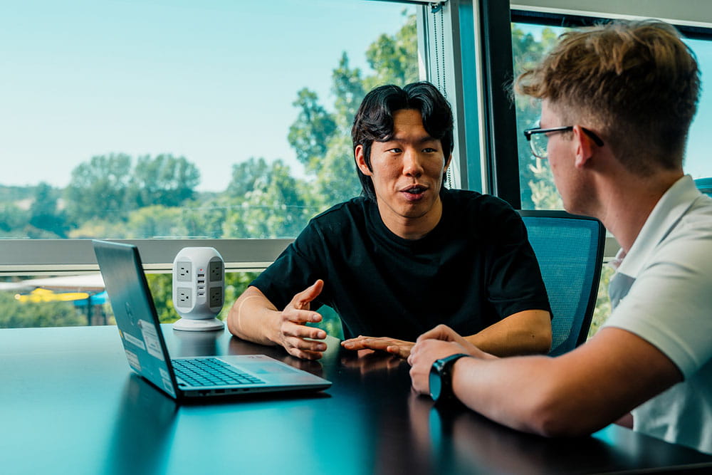 Chang Hun and a student site in front of a laptop together in a collaborative tutoring session on the Prescott Campus