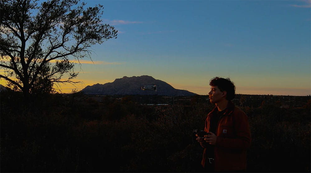 Camryn Huff stands in a park in the dessert flying a drone