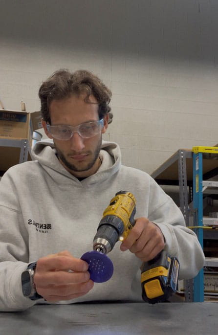 Francesco Busini uses a drill to create holes in plastic