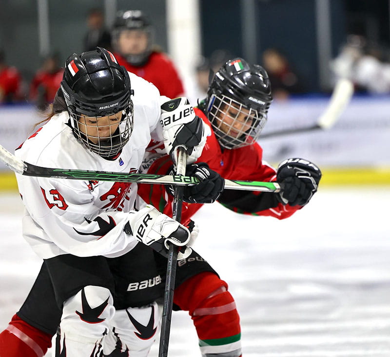 Brianna Punsalan plays hockey blocking another player on the opposing team