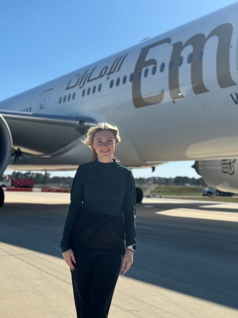 Katie Zint stands on the tarmac in front of an airplane