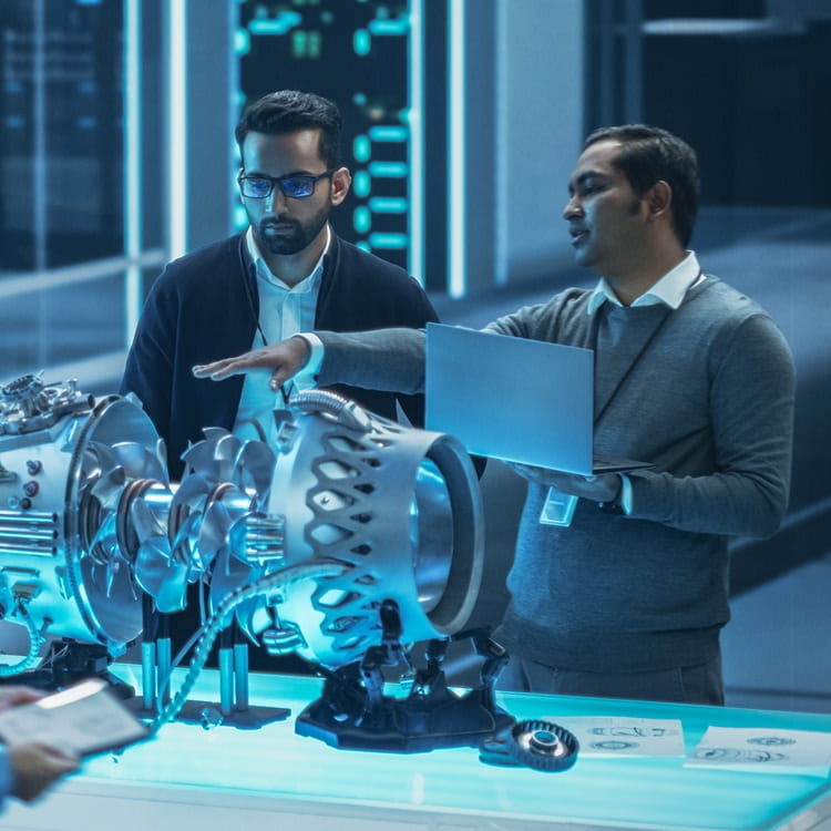 Engineer and project manager review a cutaway jet engine model, examining compressor stages, turbine section, and casing.