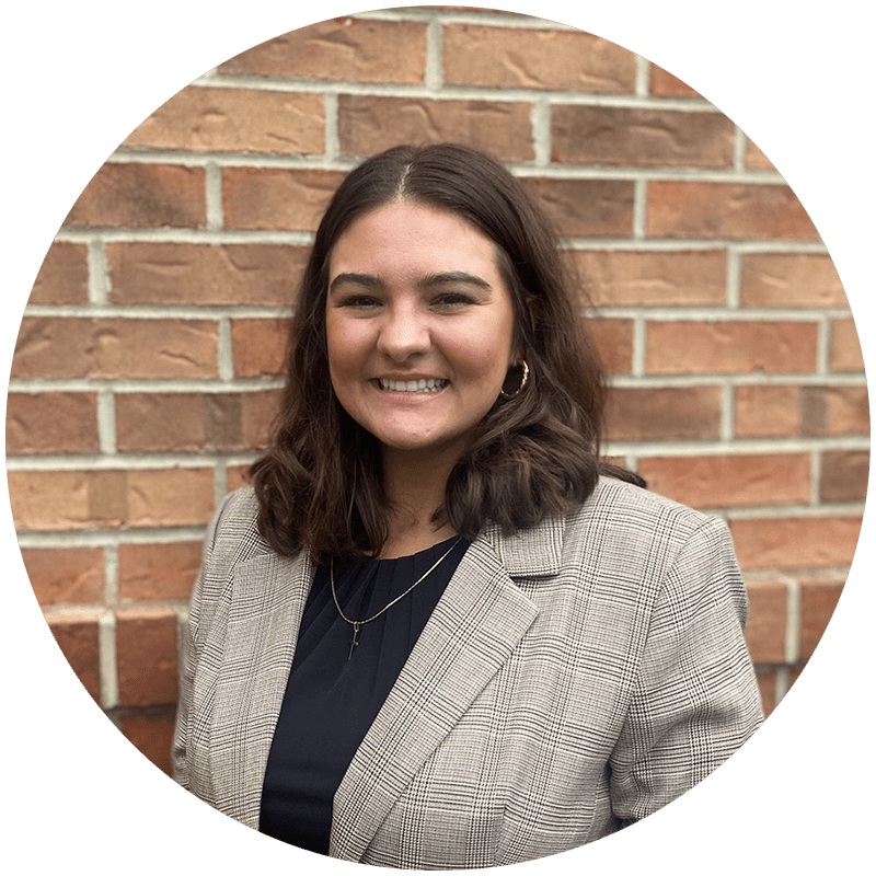 Hannah Sluder stands in front of a brick wall in professional clothing
