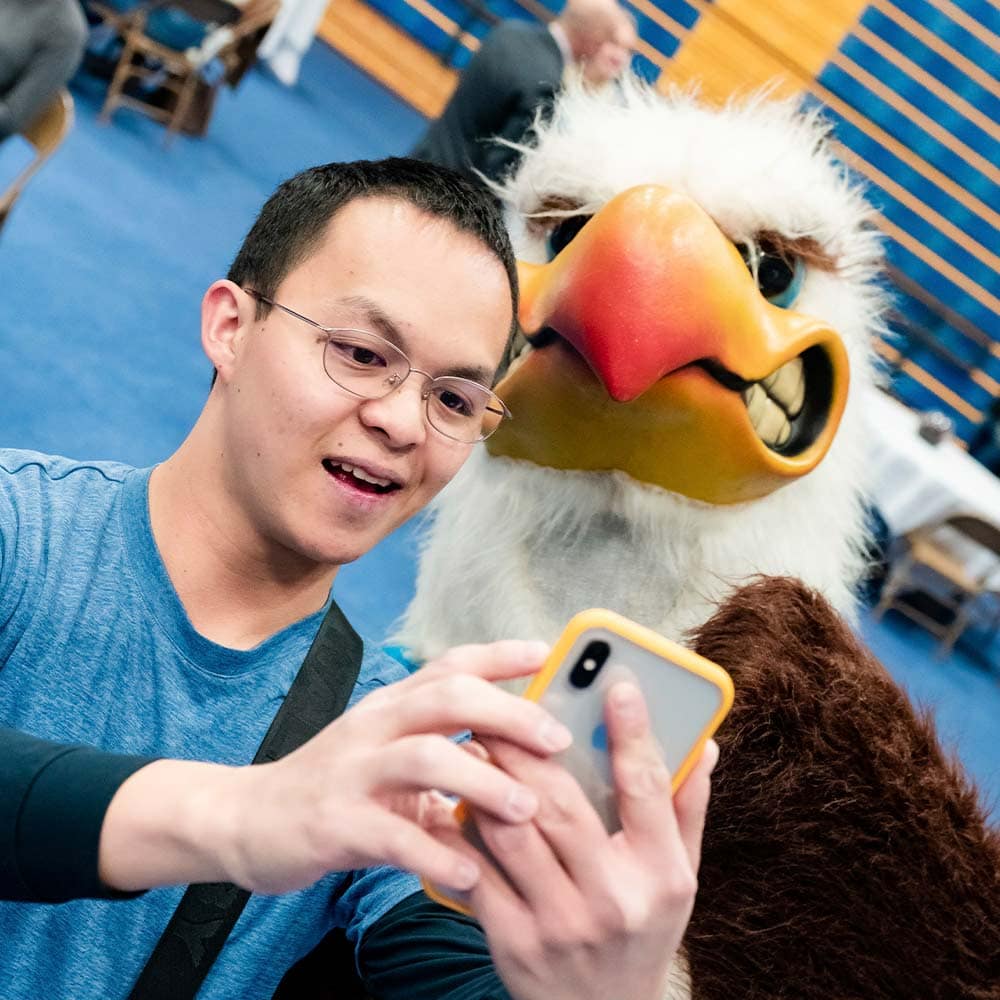 an Embry-Riddle student takes a selfie with the Eagle mascot