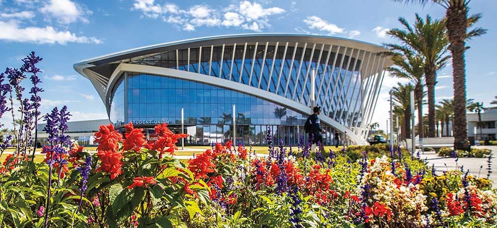 An exterior shot of an Embry-Riddle Daytona building with flowers and palm trees
