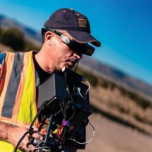 Man looks at drone monitor in desert.