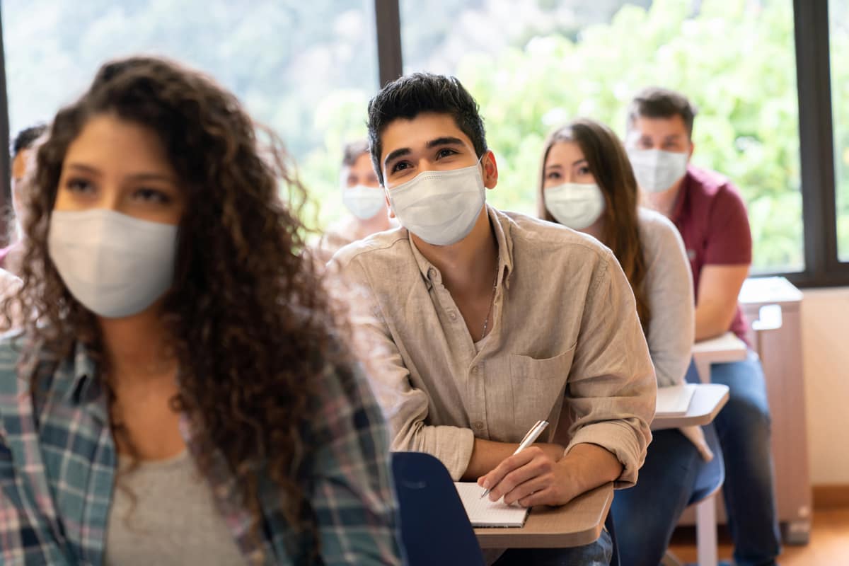 Students wearing medical mask sitting in classroom.