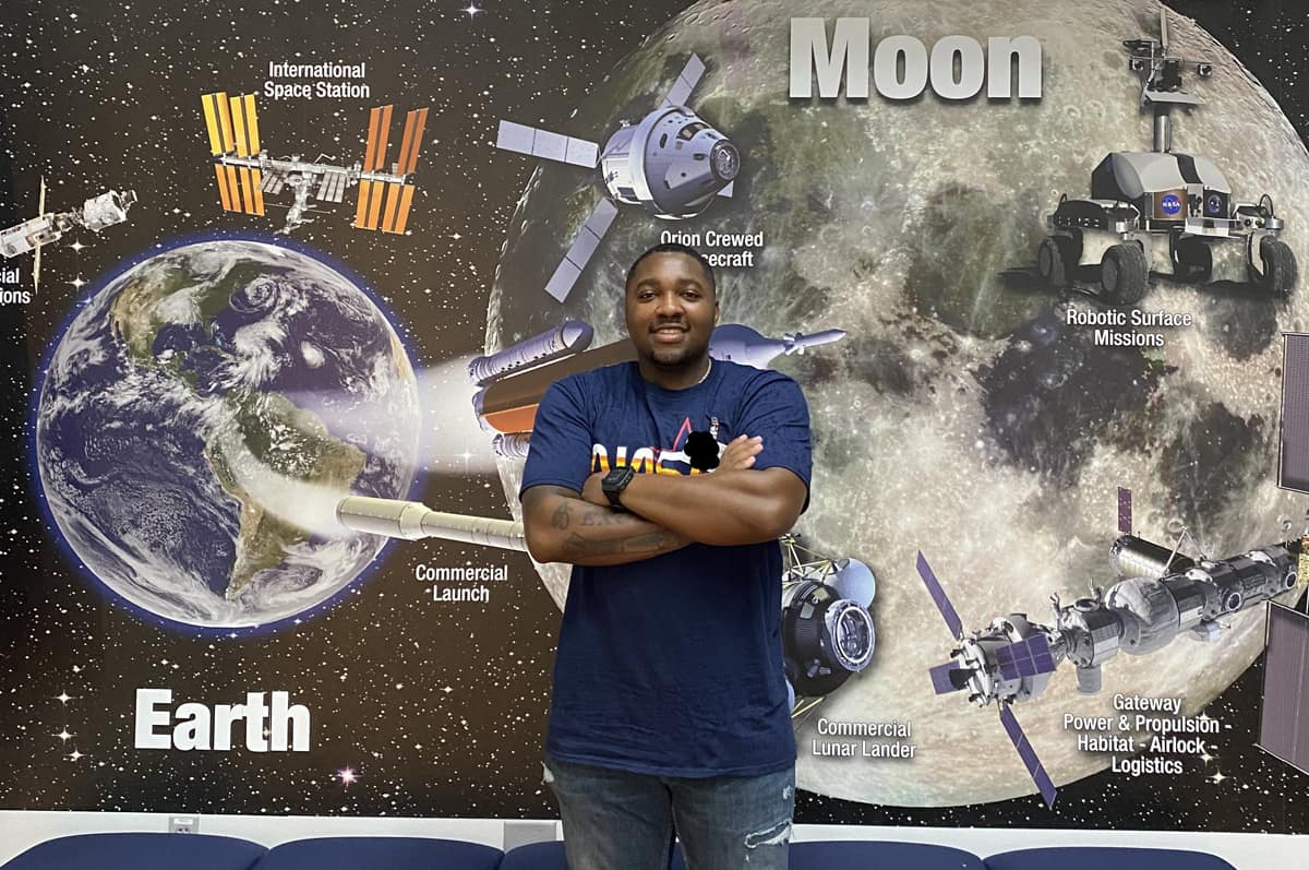 Man stands in front of picture of moon.