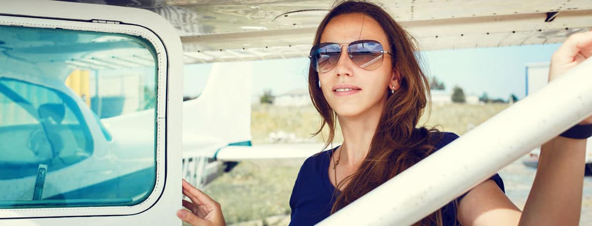 Woman stands next to plane with door open.