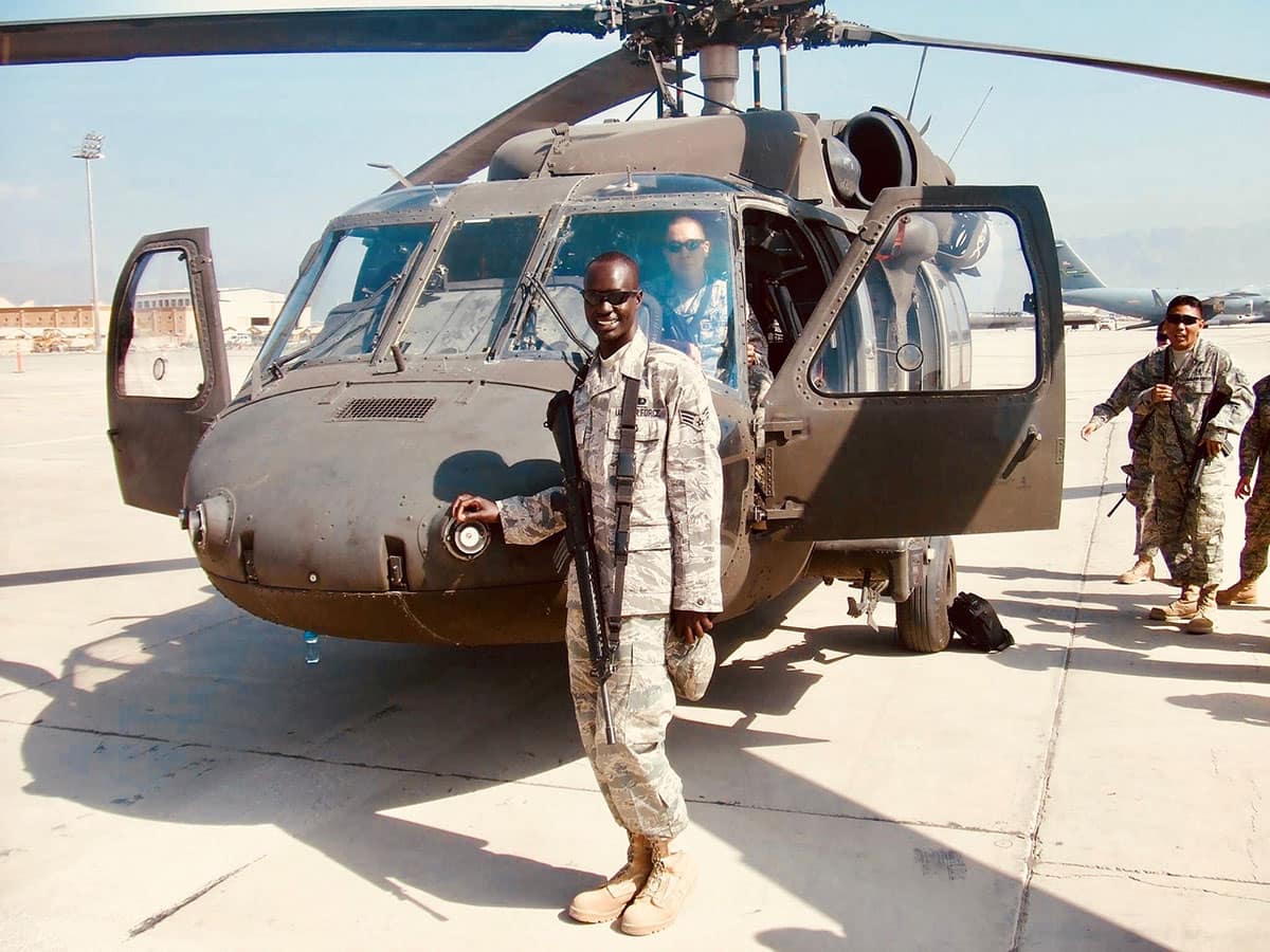 Soldier stands in front of helicopter.