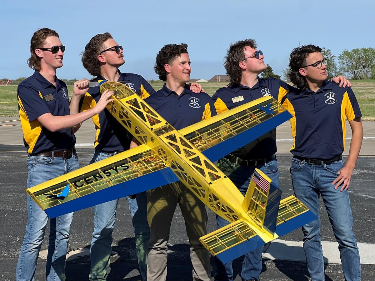 Five members of the Prescott and Daytona Campus Aircraft Design teams pose behind a small aircraft.
