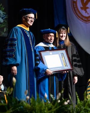 Commencement speaker awarded degree at graduation ceremony.