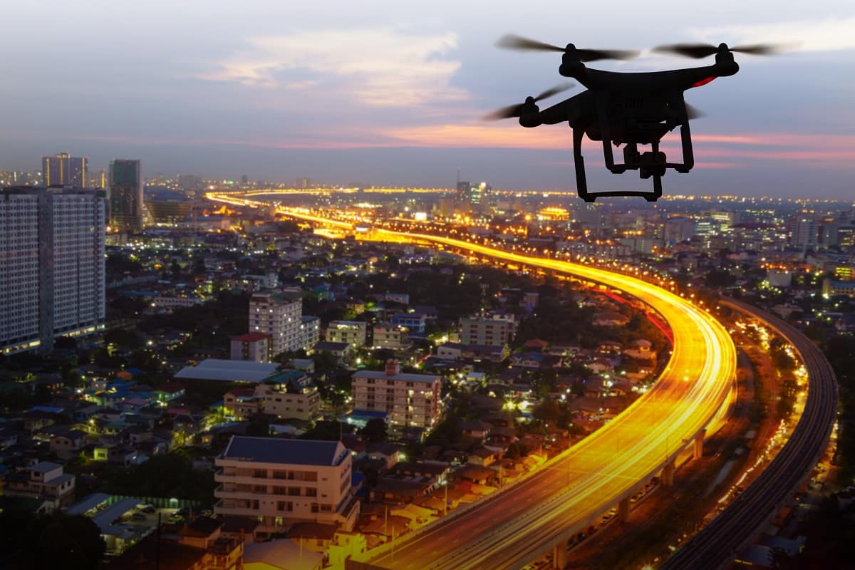 Drone flies in air over city at night.