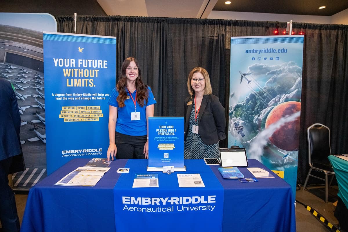 Two women in front of a convention table.
