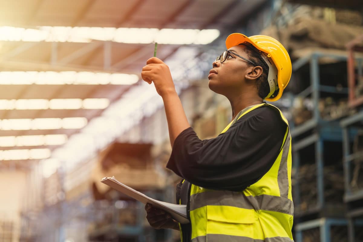 Woman in construction vest surveys a warehouse.