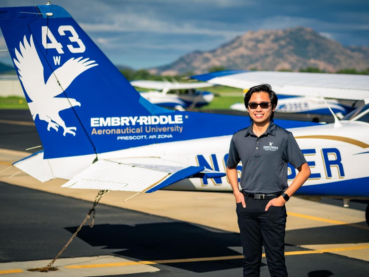 Man in front of a plane with a desert mountain background.