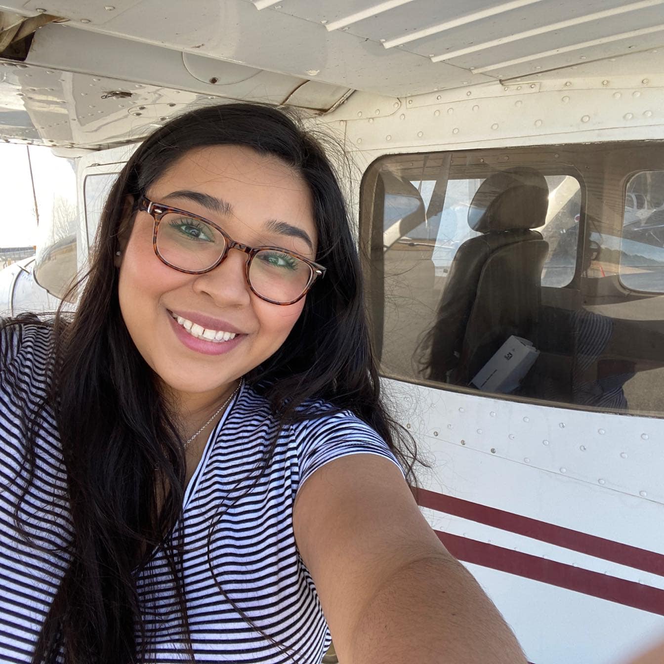Marily Aguilar poses under aircraft wing.