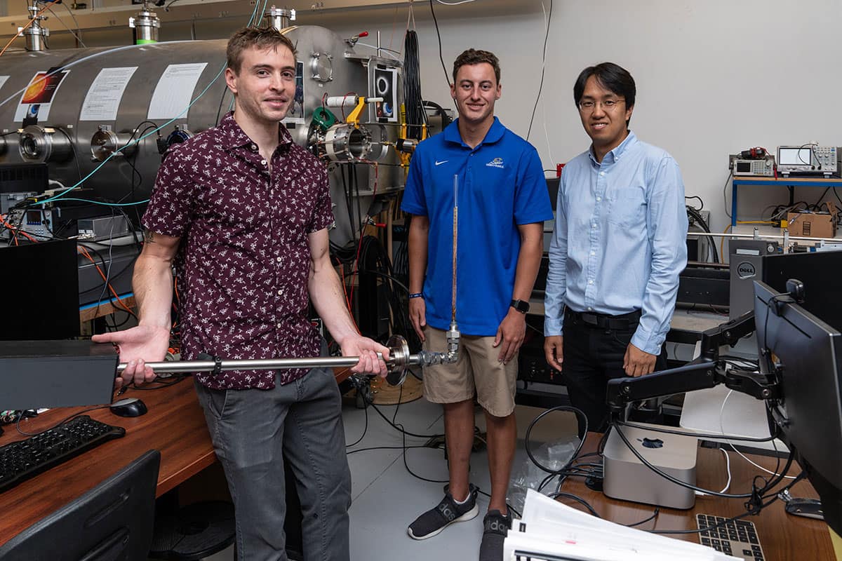Two students and professor hold lab equipment.