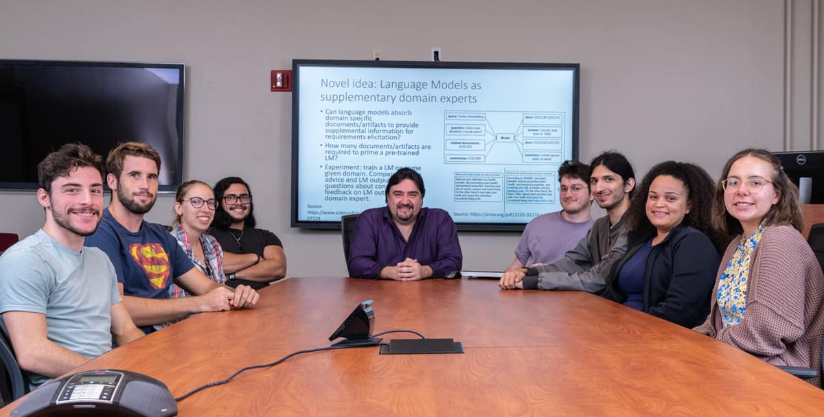 Students pose for picture sitting around table with professor.