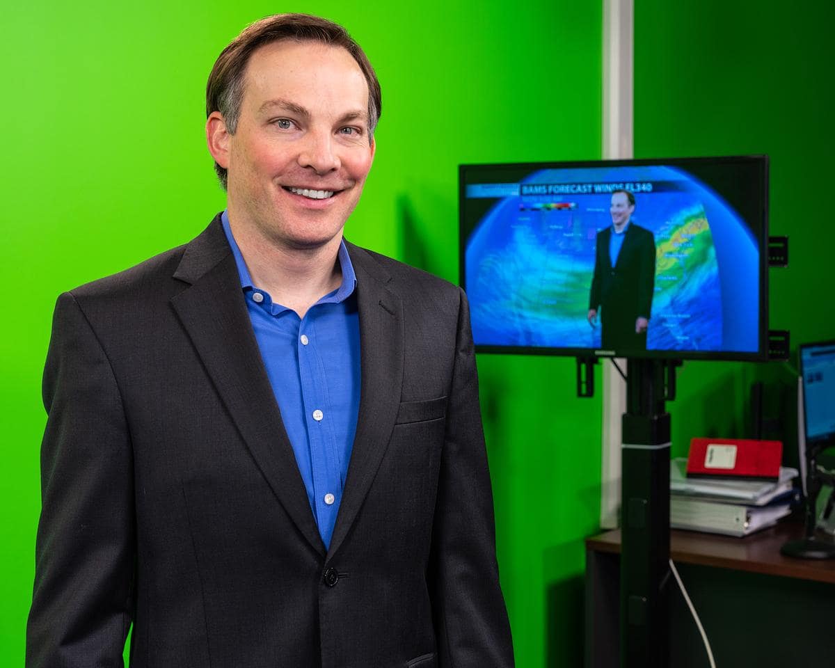 Meteorology assistant professor Rob Eicher stands in front of green screen.